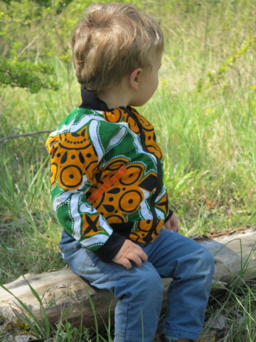 Petit garçon de 2 ans portant un bomber léger en wax orange et vert