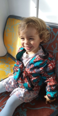 Petite fille de 3 ans portant un bomber en wax bleu et rouge doublé en sweat bio