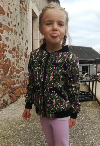 Petite fille de 4 ans portant un bomber léger en wax vert et rose